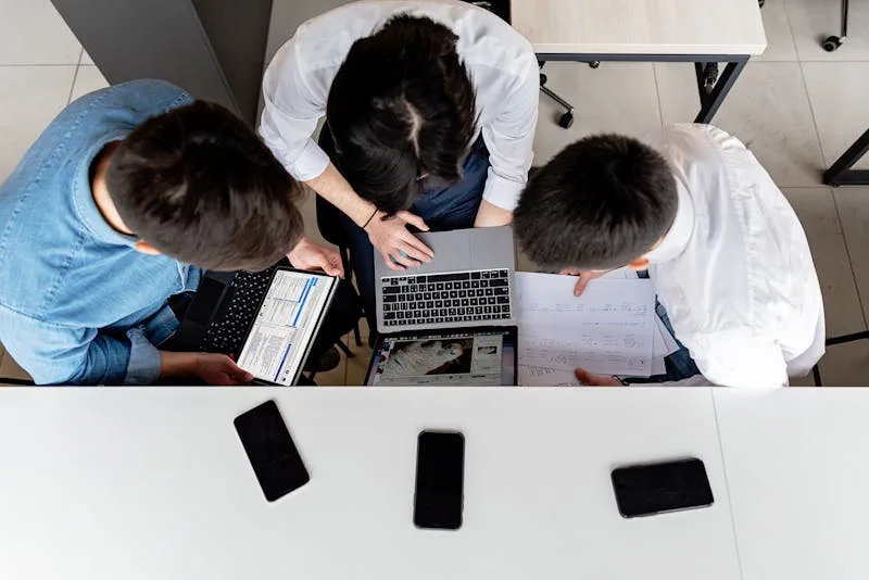 Team collaborating on documents at an office desk with laptops