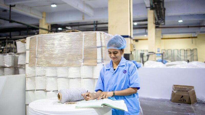 Factory worker recording quality control details in a manufacturing plant with digital document management