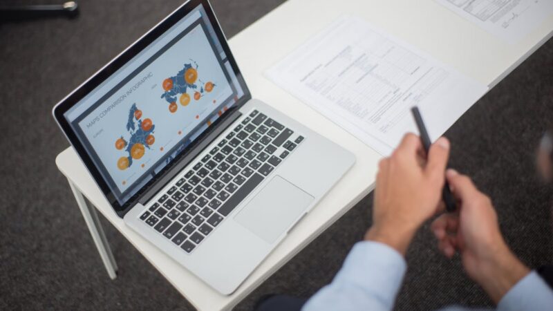 Professional analyzing document management data on a laptop in a modern office setting